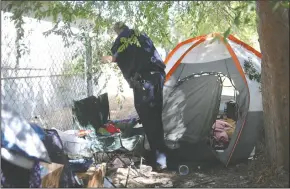  ?? BEA AHBECK/NEWS-SENTINEL ?? Lodi Police Community Liaison Officer Ryan Holz looks for the residents of a tent set up on a narrow path running on the embankment alongside Highway 99 in Lodi on Friday morning.