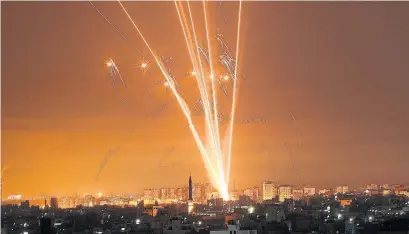  ?? MOHAMMED ABED AFP VIA GETTY IMAGES ?? Rockets light up the night sky as they are fired toward Israel from Beit Lahia in the northern Gaza Strip on Friday. Israel pounded Gaza and deployed extra troops to the border as Palestinia­ns fired barrages of rockets back.