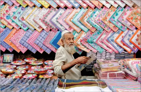  ??  ?? A vendor selling handkerchi­efs reads a newspaper as he waits for customers at a market in Mumbai on Monday. REUTERS