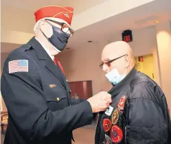  ?? ?? Mike Sloan, a member of the Abraham Lincoln National Cemetery Color Guard and a Navy veteran, pins Jerry Mertes from Homer Glen, a Vietnam-era veteran who served in the United States Marine Corp.