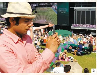  ??  ?? Sur la Henman Hill à Wimbledon, les amateurs de tennis suivaient le match de la Coupe du monde sur leur téléphone cellulaire.