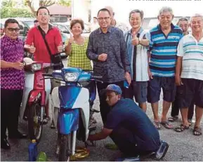  ??  ?? Mohd Puad bersama pemilik motor ketika aktiviti penyelengg­araan dan menukar minyak hitam pada program Jelajah Membara Menyantuni Rakyat di Batu Pahat, semalam.