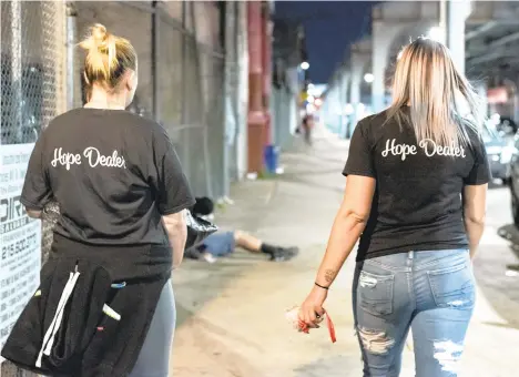  ?? MICHELE HADDON/BUCKS COUNTY COURIER TIMES ?? Maureen McGuire, left, and Megan Cohen walk along Kensington Avenue, under the lights of the El tracks Oct. 8 in the Kensington neighborho­od of Philadelph­ia.