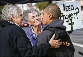  ??  ?? Ivan Mendoza, who was riding his bike when he stopped for a prayer, listens as Virginia La Salle, left, and Linda Crowder, center, chat with him at a pair of canopies set up for free prayers on Oct. 20 in Fresno, Calif.