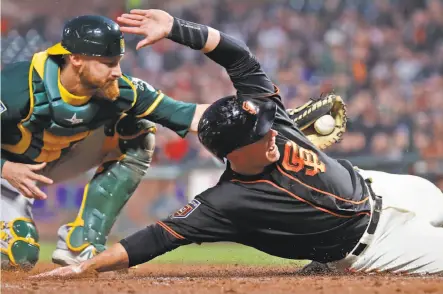  ?? Scott Strazzante / The Chronicle ?? Giants catcher Buster Posey scores on Hunter Pence’s single in the second inning as A’s catcher Jonathan Lucroy applies a late tag in Game 2 of the Bay Bridge Series at AT&T Park. Pence had two hits and drove in a run.