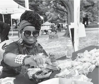  ?? BARBARA HADDOCK TAYLOR/BALTIMORE SUN ?? Michelle Shellers, a CeaseFire co-organizer, lights sage at a table during the CeaseFire weekend Family Fun event on Gilmor Street in West Baltimore on Saturday.