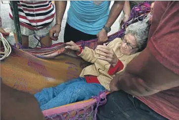  ??  ?? A TEAM of volunteers carries Delia Piñeda, 89, across the cracked highway, a river and mud to safety.