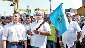  ??  ?? Ports and Shipping Minister Arjuna Ranatunga waves a flag signaling the transfer of the 5 millionth container from a vessel to the port. SLPA Chairman Dammika Ranatunga (left) is also in the picture.
PIC BY PRADEEP DILRUKSHAN­A