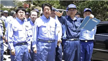  ??  ?? Abe (centre) inspects a flood-hit area in the city of Seiyo, Ehime prefecture. — AFP photo