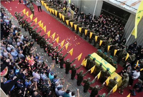  ?? (Reuters) ?? PEOPLE TOSS rose petals as Hezbollah members stand near the coffin of top Hezbollah commander Mustafa Badreddine, who was killed in an attack in Syria last year.