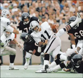  ?? Fred Jewell The Associated Press ?? Former Raiders quarterbac­k David Humm, a Bishop Gorman High product, is pulled down by Bears defensive end Richard Dent in a Nov. 5, 1984 game at Soldier Field.