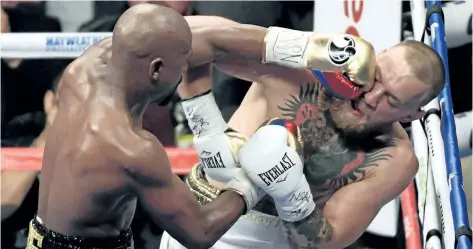  ?? ETHAN MILLER/GETTY IMAGES ?? Floyd Mayweather Jr. hits Conor McGregor in the sixth round of their super welterweig­ht boxing match at T-Mobile Arena, on Sunday, in Las Vegas. Mayweather won by 10th-round TKO.