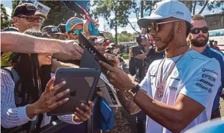  ?? EPA PIC ?? Lewis Hamilton signs autographs at Albert Park in Melbourne, Australia yesterday.