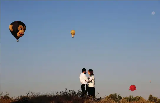  ??  ?? A COUPLE stands together as hot air balloons fly overhead during a two-day internatio­nal hot air balloon festival in Eshkol Park last July.