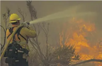  ?? MARCIO JOSE SANCHEZ/AP ?? Jesse Vasquez of the San Bernardino County Fire Department hoses down hot spots from the Bobcat Fire on Saturday in Valyermo, California.