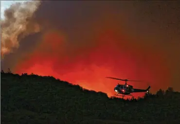  ?? GENARO MOLINA / LOS ANGELES TIMES ?? A helicopter prepares to drop water on a fire threatenin­g Santa Rosa, Calif., on Oct. 13. A recent report said the federal government has spent $350 billion over the past decade on disaster relief. That toll does not include the massive toll from this...