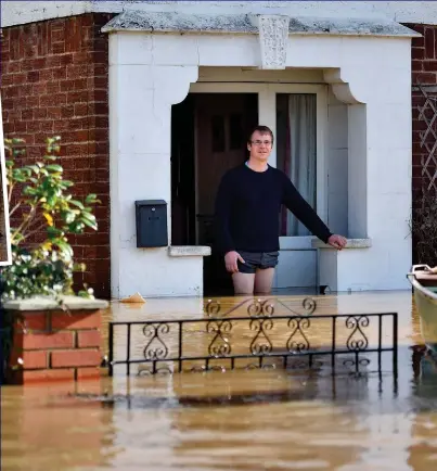  ??  ?? Help on the way: A resident stands in floodwater at his front door yesterday as a boat approaches to rescue him after the Wye rose to its highest levels in 200 years