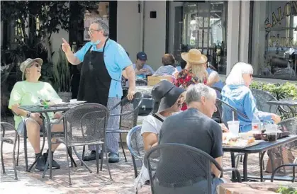  ?? RICARDO RAMIREZ BUXEDA/ORLANDO SENTINEL ?? George Paul II, owner of George’s Café, talks Monday with his customers having lunch outside the restaurant.