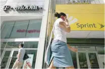  ?? — Reuters ?? A woman talks on her phone as she walks past T-mobile and Sprint wireless stores in New York.