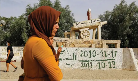  ?? AFP ?? A woman walks past a sculpture of Mohamed Bouazizi’s cart bearing the text ‘I do not forgive’ in a square named in his honour in Sidi Bouzid, central Tunisia