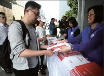  ?? PARKER ZHENG / CHINA DAILY ?? Residents collect copies of the 2018-19 Budget outside the Central Government Offices in Admiralty on Wednesday.