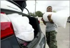  ?? JOSHUA BOUCHER/NEWS HERALD VIA AP ?? Xavier McKenzie puts a 20-pound bag of ice into his family’s car in Panama City, Fla., as Hurricane Michael approaches on Tuesday. He and his family do not live in a storm surge area, and instead prepared for losing power for days.