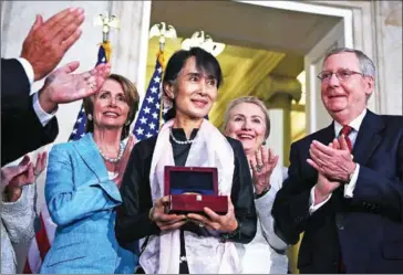  ?? ALEX WONG/AFP ?? Aung San Suu Kyi (centre) is presented with a US Congressio­nal Gold Medal in 2012 as Senator Mitch McConnell (right) applauds.