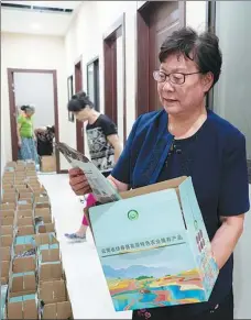  ?? GAO ERQIANG / CHINA DAILY ?? Shen Cuiying prepares boxes to pack kiwi fruit in, that she helps farmers in Dujiangyan, Sichuan province, sell in Shanghai.