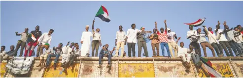  ?? DAVID DEGNER / GETTY IMAGES ?? Protesters chant above the crowds from the railroad track in Khartoum, Sudan. The railroad, built largely by the
British, has played a central part in the history of the African country.