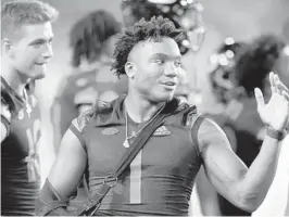  ?? WILFREDO LEE/AP ?? Hurricanes quarterbac­k D’Eriq King talks to teammates against N.C. State on Oct. 23 in Miami Gardens. King recently revealed he injured his knee Sept. 4 against Alabama.