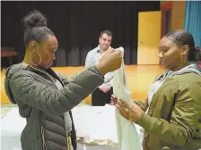  ??  ?? UNEXPECTED GIFT: Nia Simpson, left, and Regina Mendez, both 16, were among the Yawkey Boys and Girls Club of Roxbury’s Girls Group program members chosen to receive free dresses for the holiday.