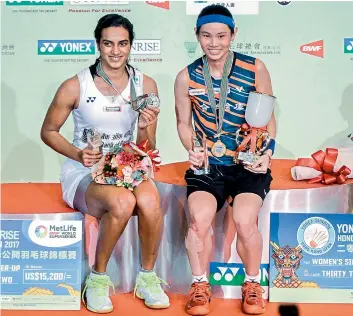  ?? — AFP ?? Runner-up P. V. Sindhu (left) and winner Tai Tzu Ying of Taiwan pose with their women’s singles trophies at the Hong Kong Open on Sunday. Sindhu went down fighting 18-21, 18-21 in the final.