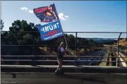  ?? PHOTO BY MARTHA ROSS ?? A man who wouldn’t give his name but who says he lives locally, skates across the El Curtola overpass above Highway 24, waving a Trump sign, in Lafayette in November.