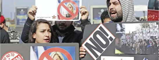  ?? — AP ?? BEIRUT: Lebanese communist protesters hold placards with Arabic that read, ‘You are not welcome’ during a protest against France’s far-right presidenti­al candidate Marine Le Pen’s visit, in Beirut yesterday.