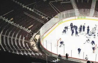  ?? Jonathan Hayward / Associated Press ?? The Vancouver Canucks conduct practice as workers prepare to cover empty seats at Rogers Arena. Roughly half of the NHL’s revenue comes from inarena elements such as ticket sales.