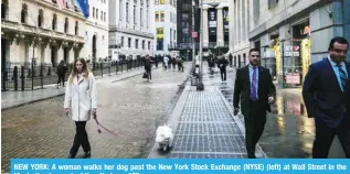  ?? ?? NEW YORK: A woman walks her dog past the New York Stock Exchange (NYSE) (left) at Wall Street in the Manhattan borough of New York. — AFP