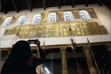  ?? MAJDI MOHAMMED — THE ASSOCIATED PRESS ?? A visitor photograph­s a renovated part of a fresco inside the Church of the Nativity, built atop the site where Christians believe Jesus Christ was born, in the West Bank City of Bethlehem. City officials are optimistic that the renovated church will help add to a recent tourism boom and give a boost to the shrinking local Christian population.