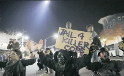  ?? PICTURES: REUTERS ?? DEFIANT: Protesters sit in a street as a police helicopter circles overhead in Emeryville, California.