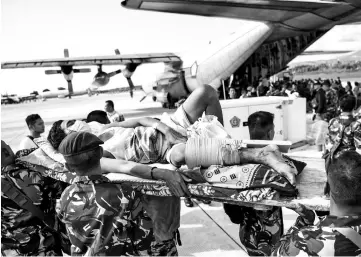  ??  ?? An injured man is evacuated on a military aircraft at Mutiara Sis Al Jufri Airport in Palu. — Reuters photo