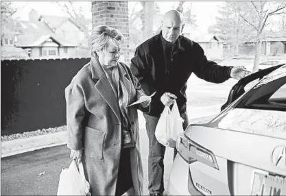  ?? GARY MIDDENDORF/DAILY SOUTHTOWN ?? Jan Hill looks over a list of seniors as husband Joe Matula grabs a bagged meal on their Monday morning route for PLOWS Council on Aging.