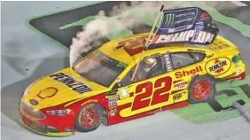  ?? AP PHOTO/DAVID GRAHAM ?? NASCAR driver Joey Logano celebrates with a burnout Sunday night at Homestead-Miami Speedway. Logano delivered a Cup Series title for Team Penske and Ford by winning the season finale despite his underdog status.