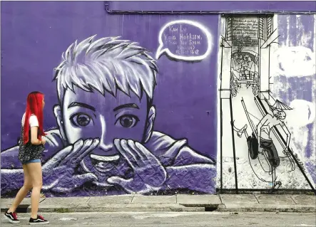  ?? Associated Press photo ?? A woman looks at street art on a wall in George Town on the island of Penang, Malaysia. George Town oozes a hauntingly rustic charm, with colourful street art as much a draw as the historical architectu­re and one of Southeast Asia’s tastiest street...