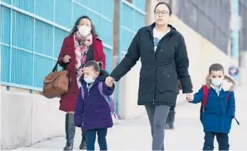  ?? SETH WENIG/AP ?? Young children wearing face masks are taken to a school on March 7 in New York.