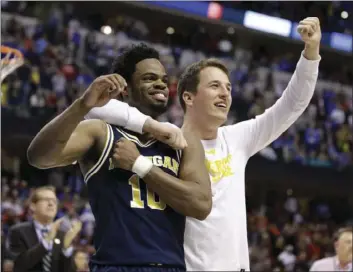  ??  ?? Michigan guard Derrick Walton Jr. (left) and guard Andrew Dakich celebrate following a 73-69 win over Louisville on Sunday in Indianapol­is. AP PHOTO