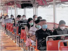  ?? CHONMAHATR­AKOOL ARNUN ?? People wearing masks ride a Chao Phraya express boat.