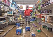  ?? RYAN C. HERMENS/LEXINGTON HERALD-LEADER VIA ASSOCIATED PRESS ?? Gwen Christian stands Monday in a flooded aisle at an IGA grocery store in Isom, Ky. Christian began working at the store as a cashier months after it first opened in 1973. She now owns the store with her husband, Arthur.
