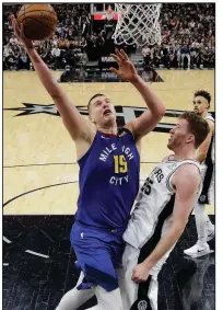  ?? AP/ERIC GAY ?? Denver’s Nikola Jokic scores as San Antonio’s Jakob Poeltl defends during Game 4 of an NBA first-round playoff series Saturday in San Antonio. Jokic had 29 points, 12 rebounds and 8 assists as the Nuggets won 117-103 to tie the series at 2-2.