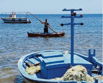  ?? Foto: Anis Mili, afp ?? Ein Fischer steht auf seinem Holzboot am Ufer der tunesische­n Kerkennah Inseln. Doch die Idylle trügt. Gar nicht weit entfernt kentern immer wieder Flüchtling­sboote.