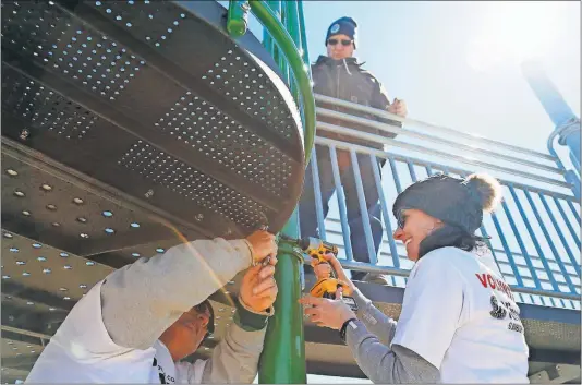  ?? [ADAM CAIRNS/DISPATCH PHOTOS] ?? With help from Jeff Norton, above, and Gene Linton, left, Amy Ranalli uses an impact driver to bolt down a panel on a play set at the Souders Community Playground located behind Hylen Souders Elementary School in Galena. A group of volunteers has been working for several days to assemble the playground that is able to be used by those with physical disabiliti­es. The playground was inspired by Ranalli’s son, Marco, who has limited use of his arms.