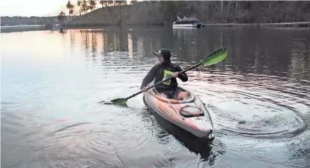  ?? PAUL A. SMITH / MILWAUKEE JOURNAL SENTINEL ?? Mick Lewski of Oak Creek paddles his kayak away from the public access on Beaver Lake in Hartland on opening day of the Wisconsin fishing season.